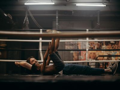 Close up of a person stretching in a dark gym