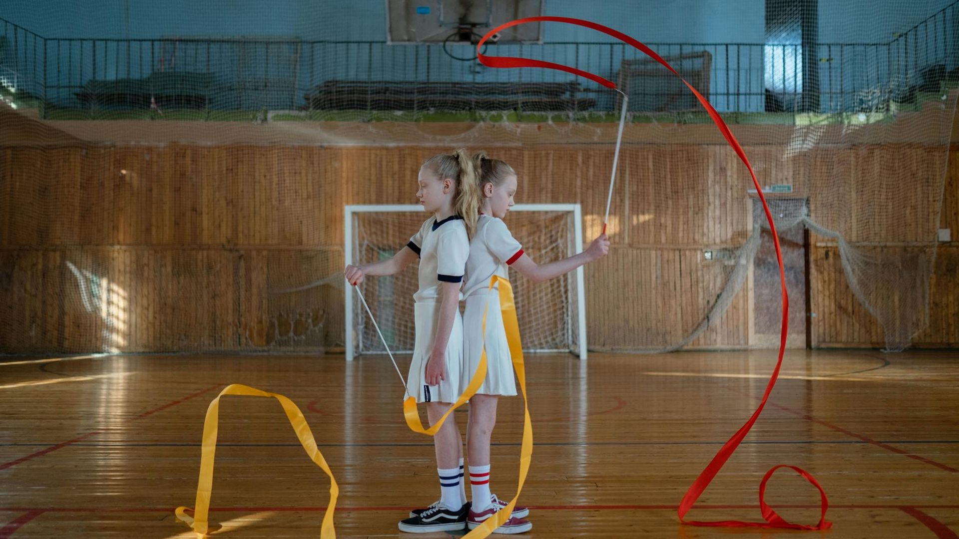 Person performing dynamic rhythmic movements in a dark modern gym
